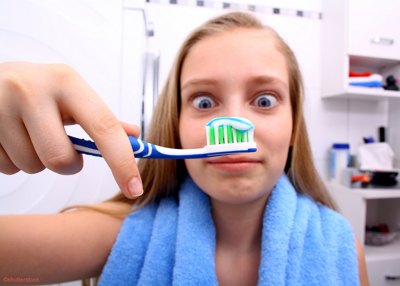 girl holding a tooth brush looking at it cross-eyed