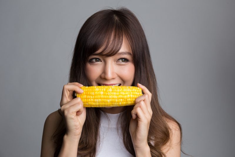 Woman biting into a corn cob without hurting her teeth