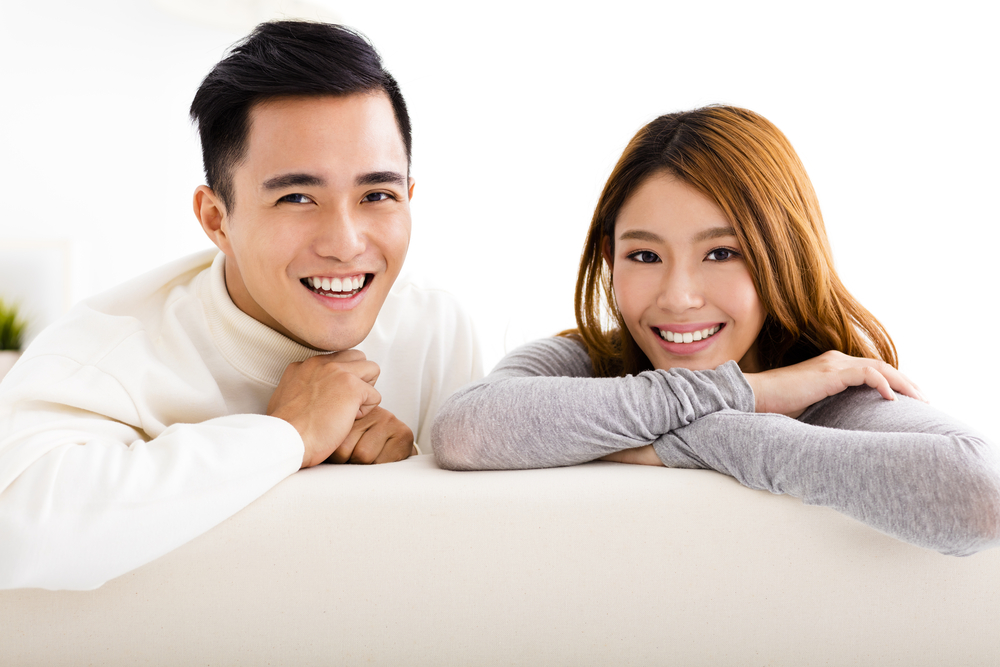 Young happy couple sitting inside on their couch