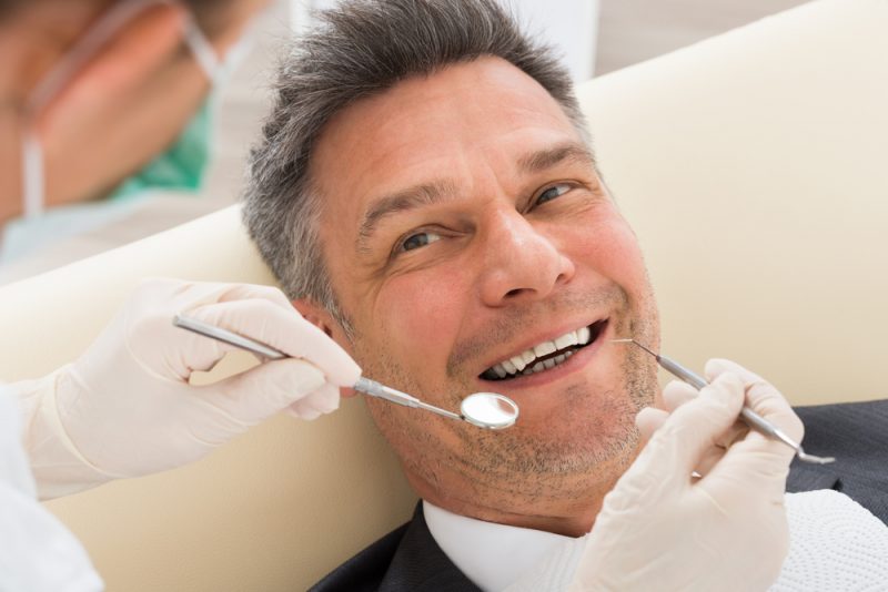 Man smiling while getting a dental exam