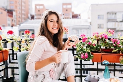 Young woman sitting on her balcony in the summer sun