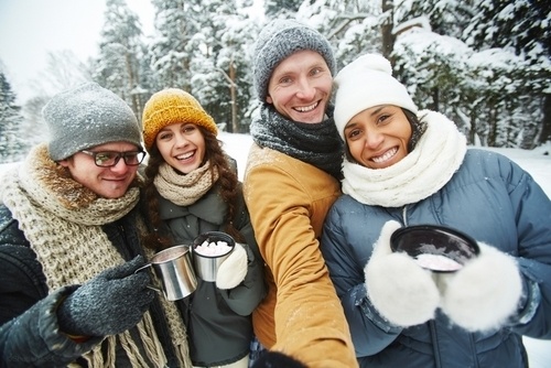 Two couples smiling in winter clothing in the snow