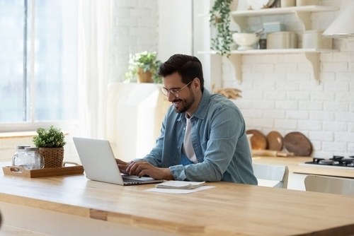 man at home on computer smiling while working