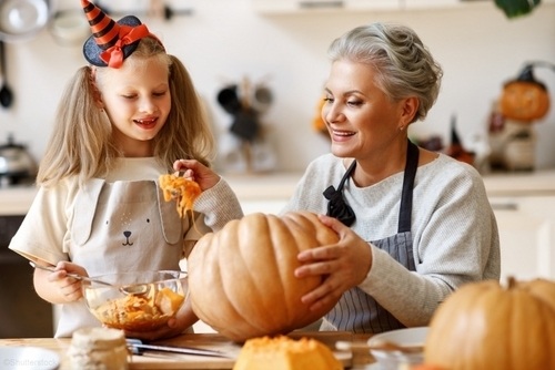 young girl and grandmother carving pumpkins in the kitchen